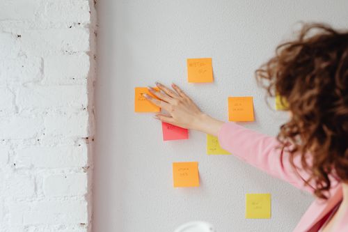 Une personne colle des post-its colorés sur un mur pendant une séance de planification