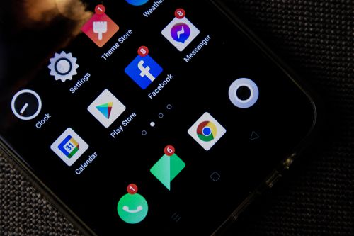 Un smartphone tenu en main montre plusieurs icônes d’applications de réseaux sociaux