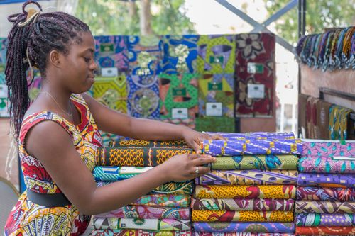 Une vendeuse étale des tissus colorés sur son stand de marché, à Cotonou